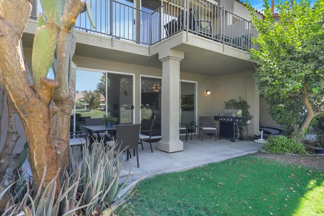 a view of a patio with table and chairs potted plants and floor to ceiling window