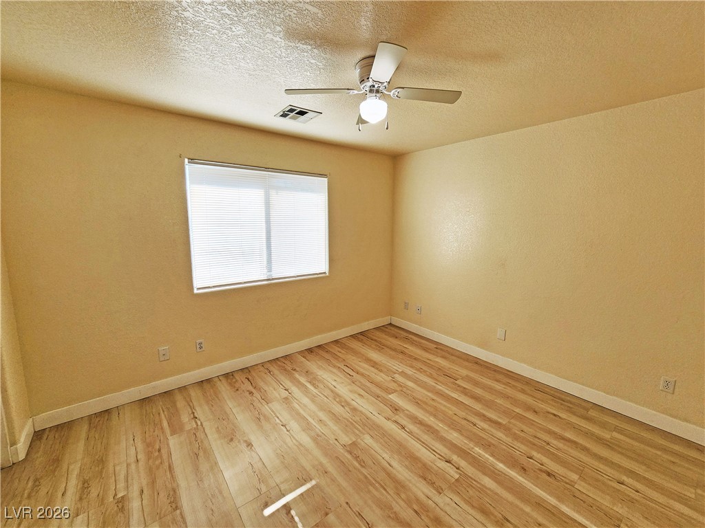 1081 Marne Court, Unit C Pahrump, NV 89048 - Photo 16 of 22 Unfurnished room with light wood finished floors, a textured ceiling, ceiling fan, and a textured wall
