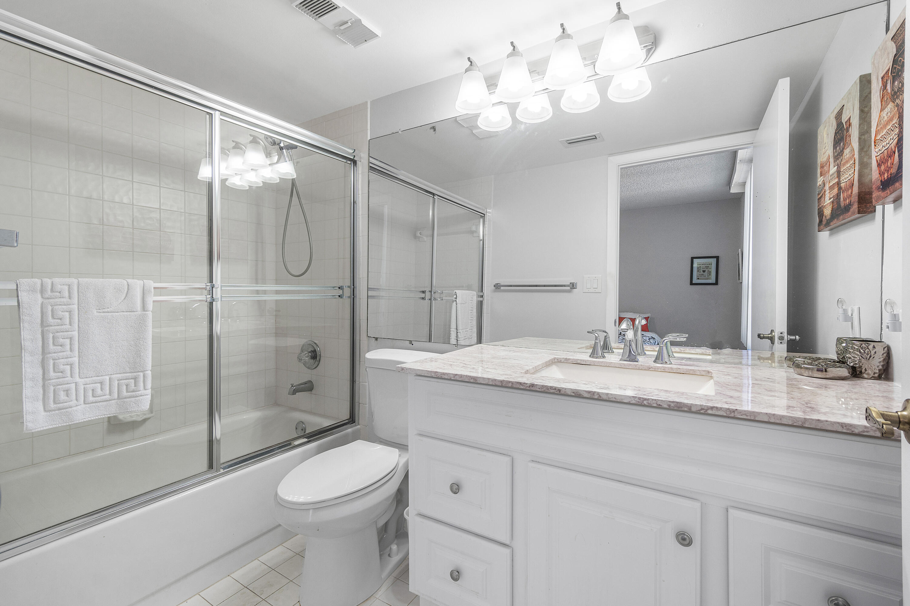 7572 Regency Lake Drive, Unit 401 Boca Raton, FL 33433 - Photo 20 of 28 a bathroom with a granite countertop sink a toilet and a mirror