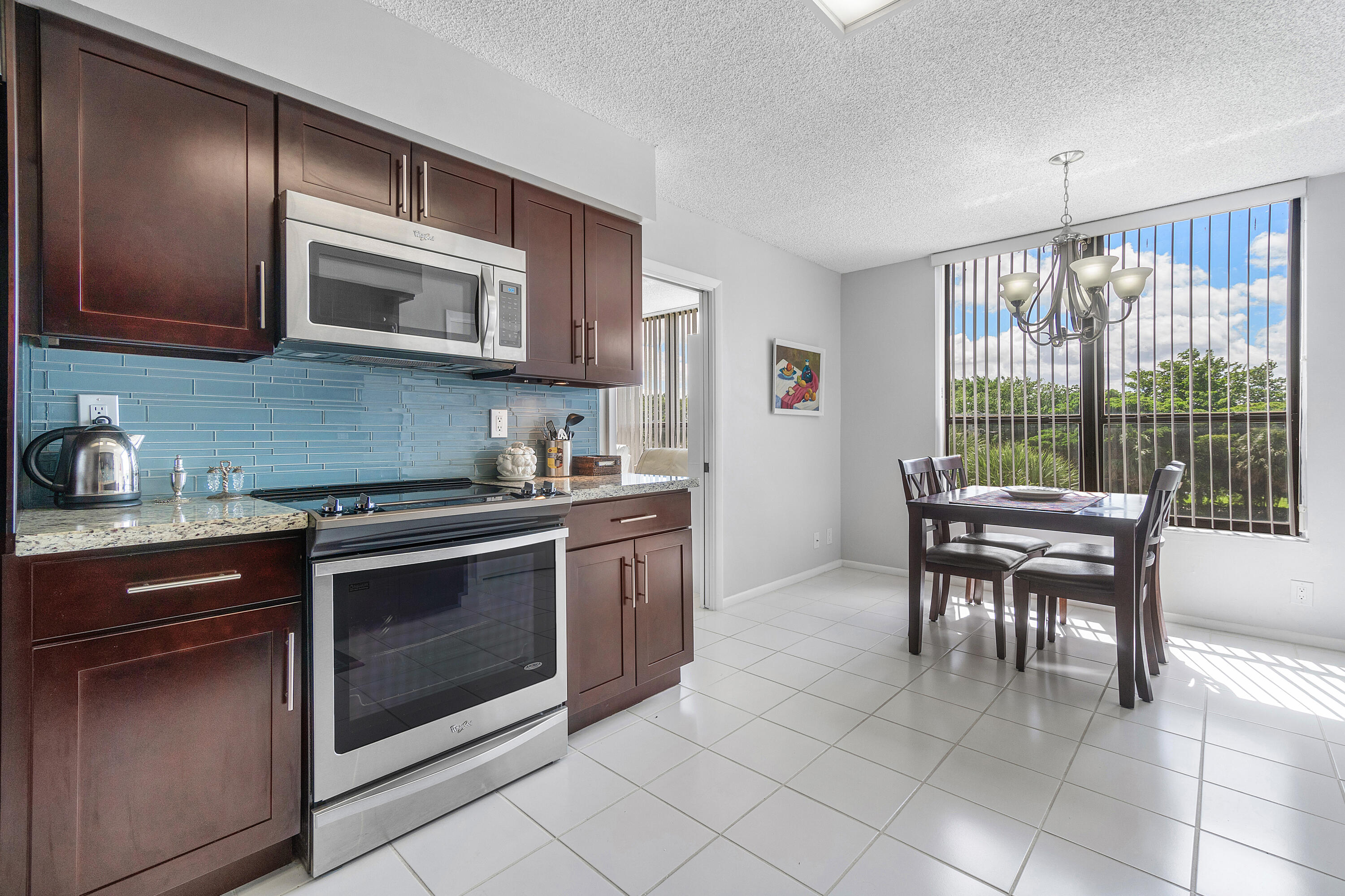 7572 Regency Lake Drive, Unit 401 Boca Raton, FL 33433 - Photo 8 of 28 a kitchen with stainless steel appliances granite countertop a stove a sink and a microwave