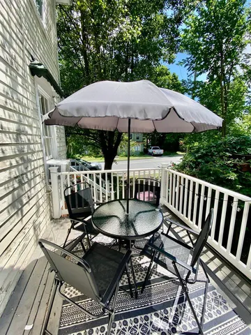 a patio with wooden floor a yard a table and chairs