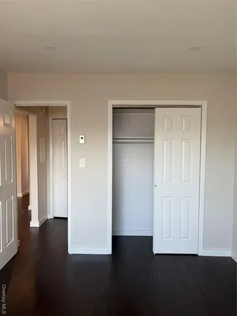 an empty room with wooden floor & closet area