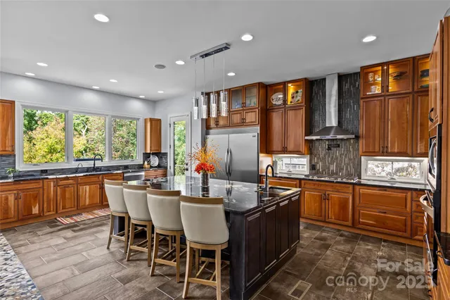 a kitchen with stainless steel appliances granite countertop a stove a sink dishwasher a dining table and chairs with wooden floor