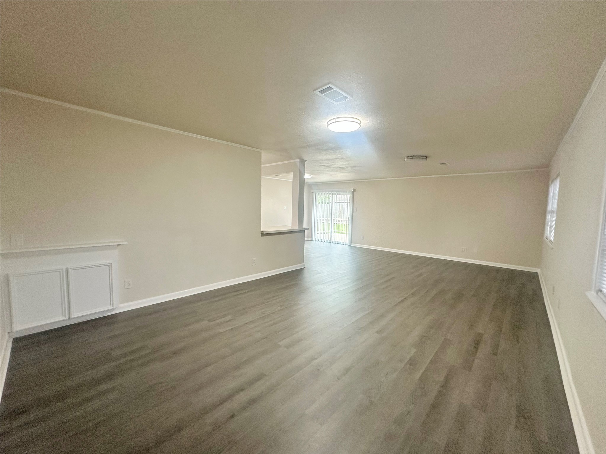 130 Bay Ridge Drive Baytown, TX 77523 - Photo 5 of 20 This spacious room features modern flooring, neutral walls, and ample natural light from large windows. The open layout is ideal for versatile living and entertaining, complemented by a ceiling light fixture and sliding glass door leading to outdoor space.