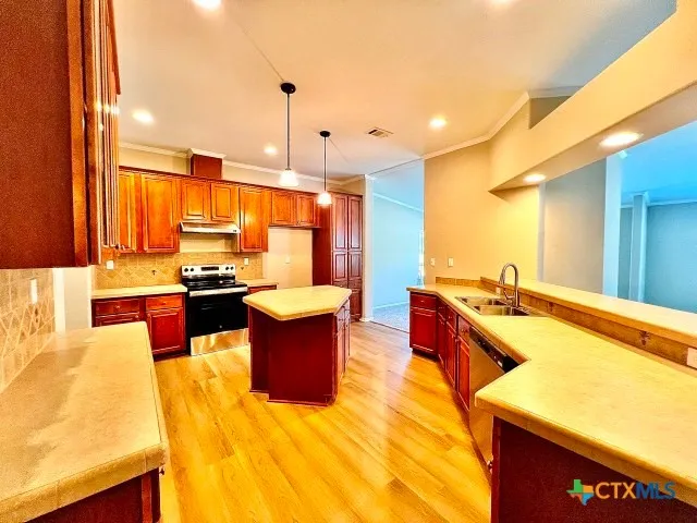 a large kitchen with kitchen island a large counter top space a sink stainless steel appliances and cabinets