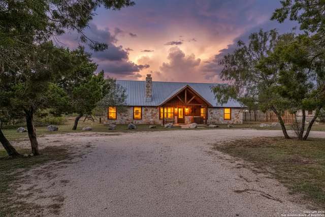 a view of a large house with large trees and wooden fence