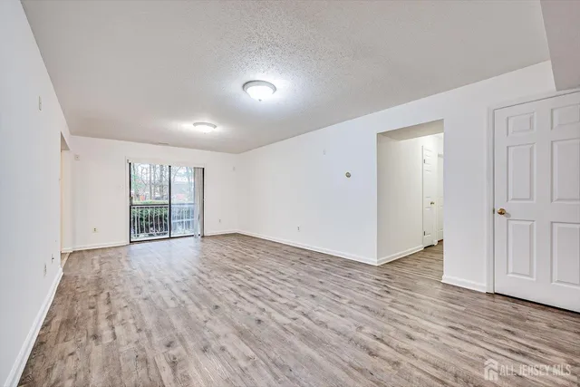 a view of an empty room with wooden floor and window