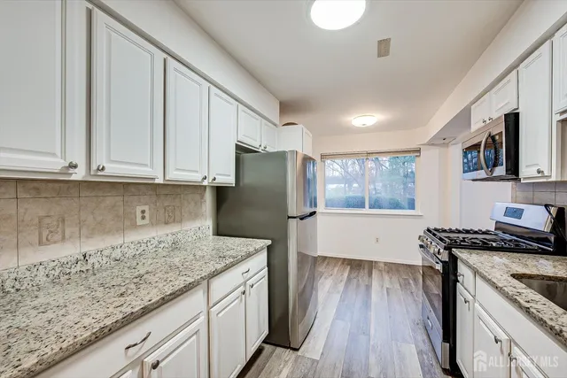 a kitchen with granite countertop a stove a sink dishwasher and a refrigerator with wooden floor
