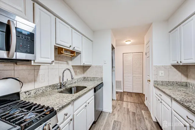 a kitchen with granite countertop a sink stove and cabinets