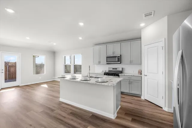 a kitchen with stainless steel appliances granite countertop a refrigerator and a stove top oven