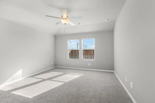 an empty room with chandelier fan and windows