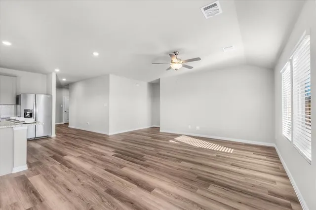 a view of kitchen and empty room with wooden floor