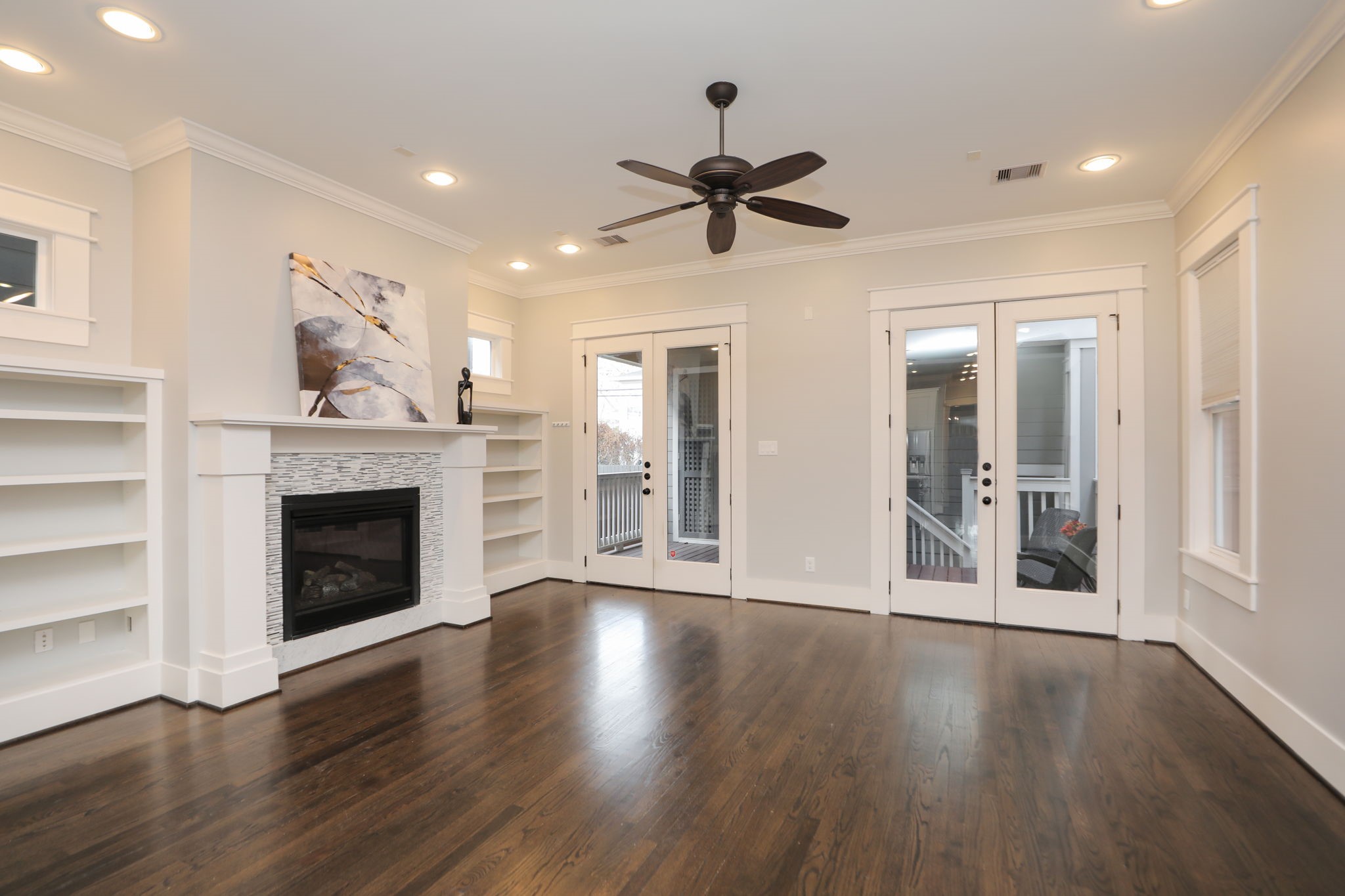 907 East 25th Street Houston, TX 77009 - Photo 10 of 32 Large family room has built in shelves, stately fireplace, high ceilings, beautiful hardwood floors and crown molding. Both double doors lead to outdoor deck.