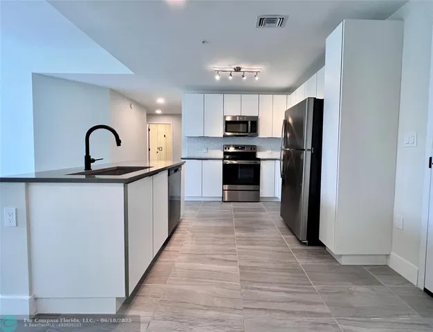 a view of kitchen with stainless steel appliances granite countertop a refrigerator and a sink