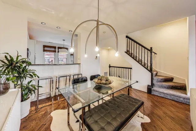 a kitchen with stainless steel appliances granite countertop a refrigerator a stove a sink and a dining table with wooden floor