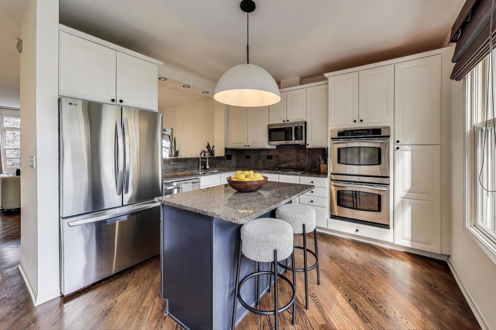 1009 North Riverwalk Street Chicago, IL 60610 - Photo 13 of 39 a kitchen with stainless steel appliances granite countertop a refrigerator a stove a sink and a dining table with wooden floor