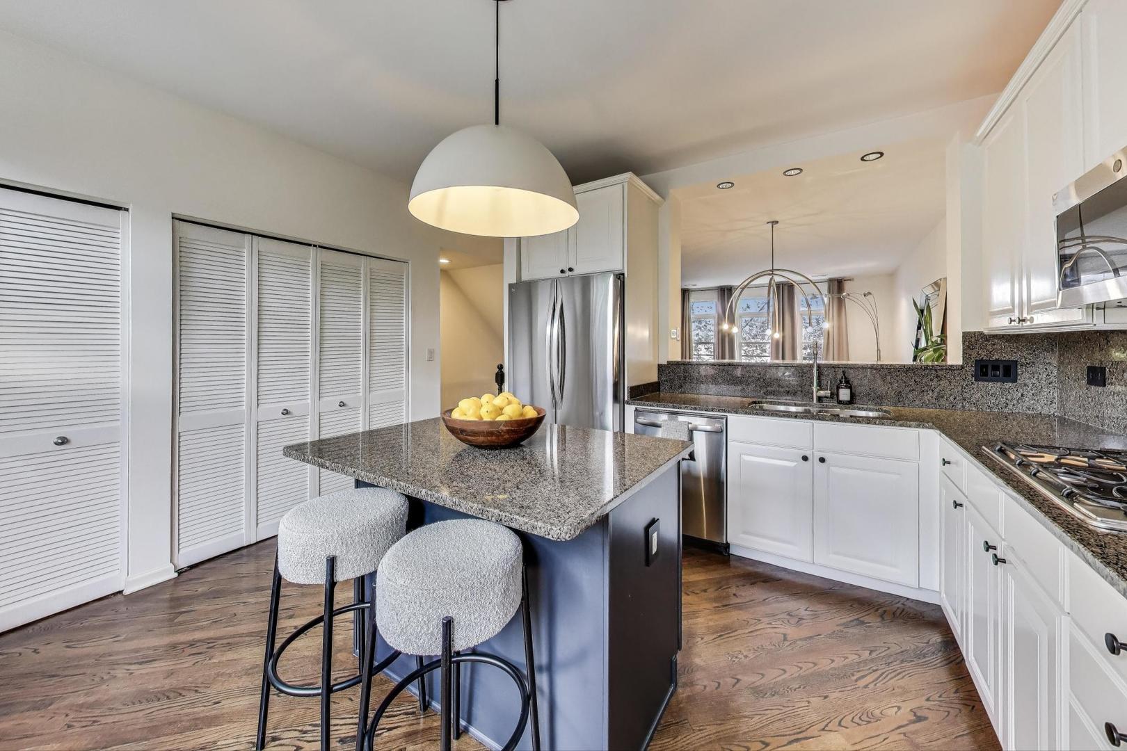 1009 North Riverwalk Street Chicago, IL 60610 - Photo 16 of 39 a kitchen with stainless steel appliances granite countertop a sink a stove a refrigerator a dining table and chairs with wooden floor