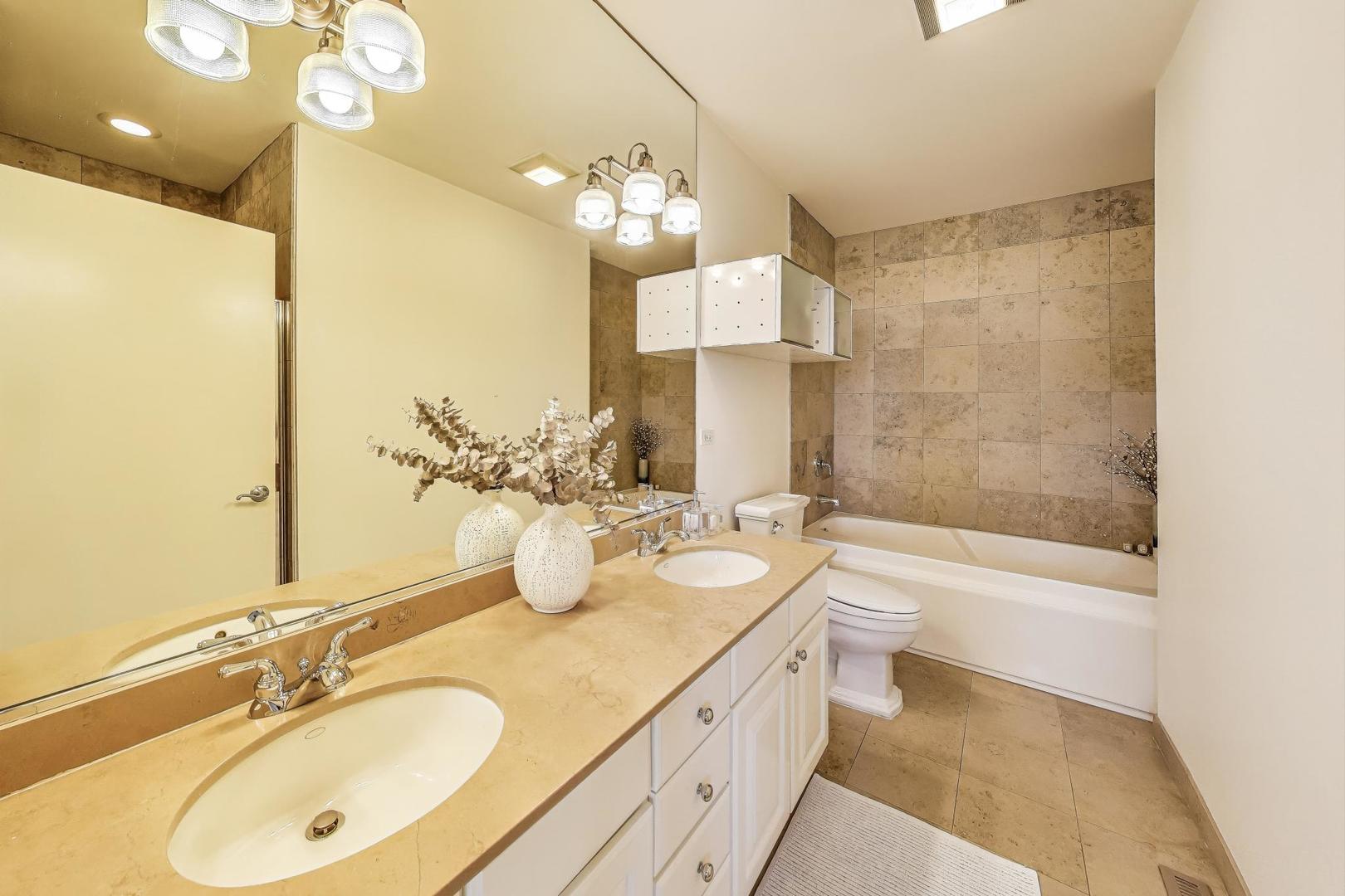 1009 North Riverwalk Street Chicago, IL 60610 - Photo 22 of 39 a bathroom with a double vanity sink a toilet a mirror and shower