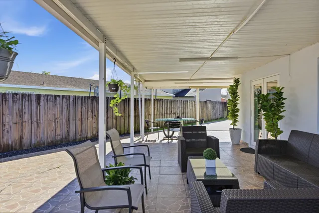 a living room with patio furniture and potted plants
