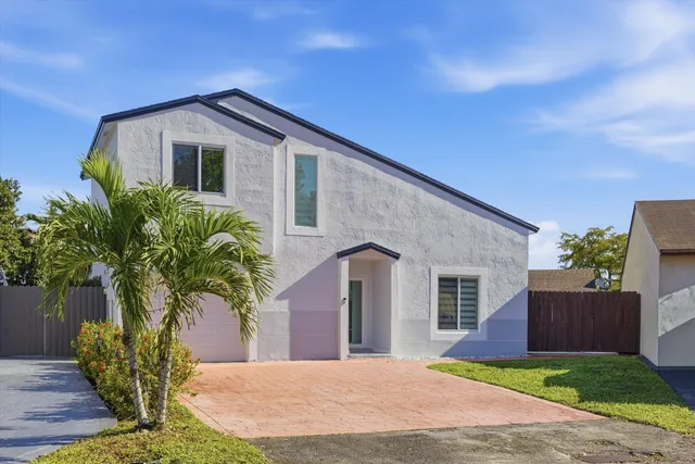 a front view of a house with a yard and potted plants