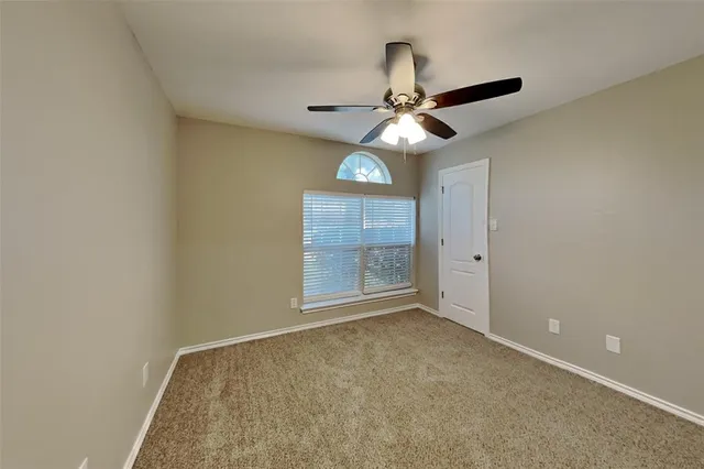 an empty room with a ceiling fan and a window