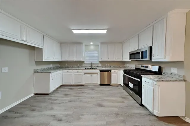 a kitchen with granite countertop white cabinets and stainless steel appliances