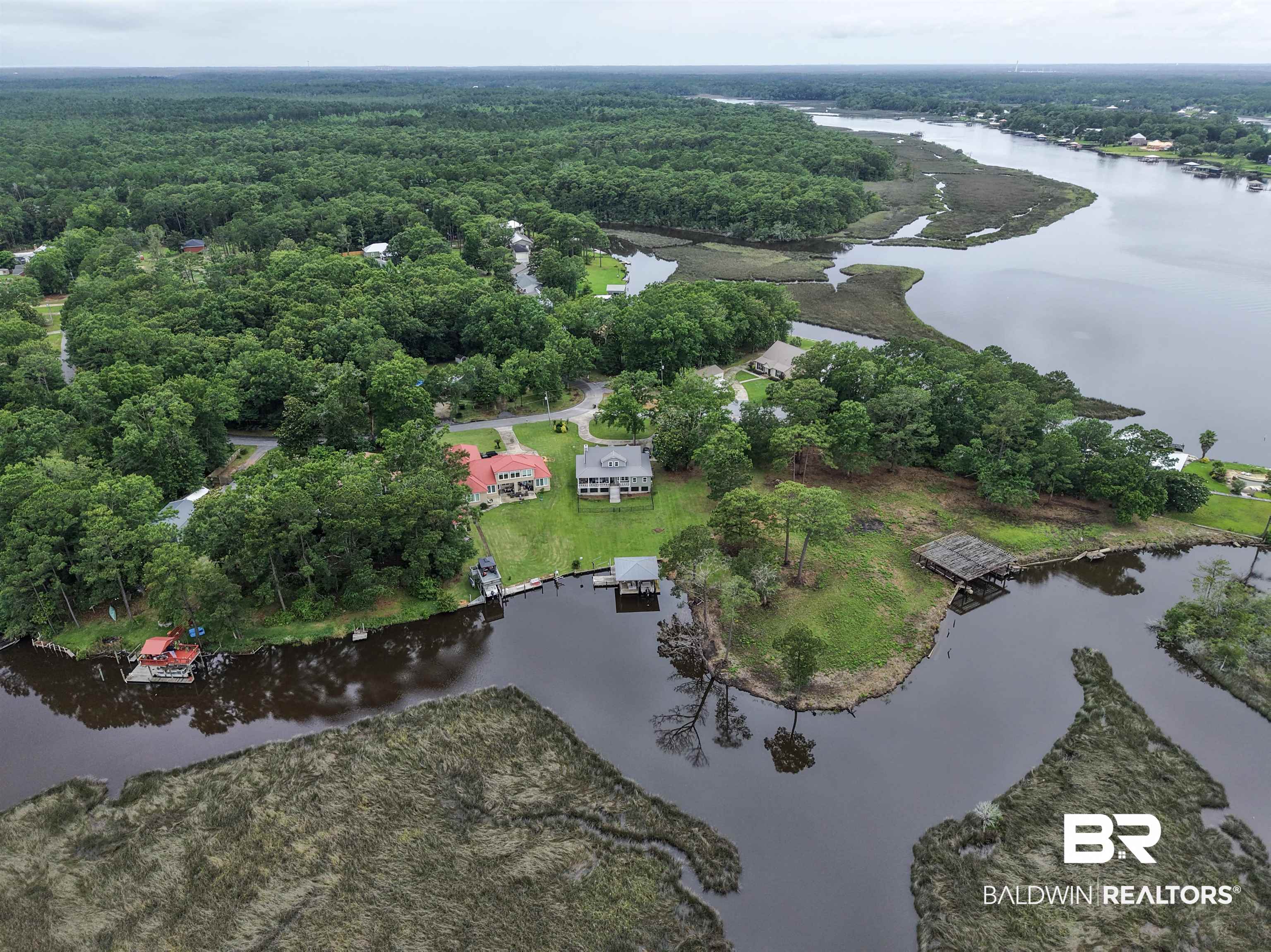 12171 Marguerite Drive Coden, AL 36523 - Photo 31 of 44 Expansive waterfront property featuring a two-story residence with a green lawn, mature trees, and direct water access