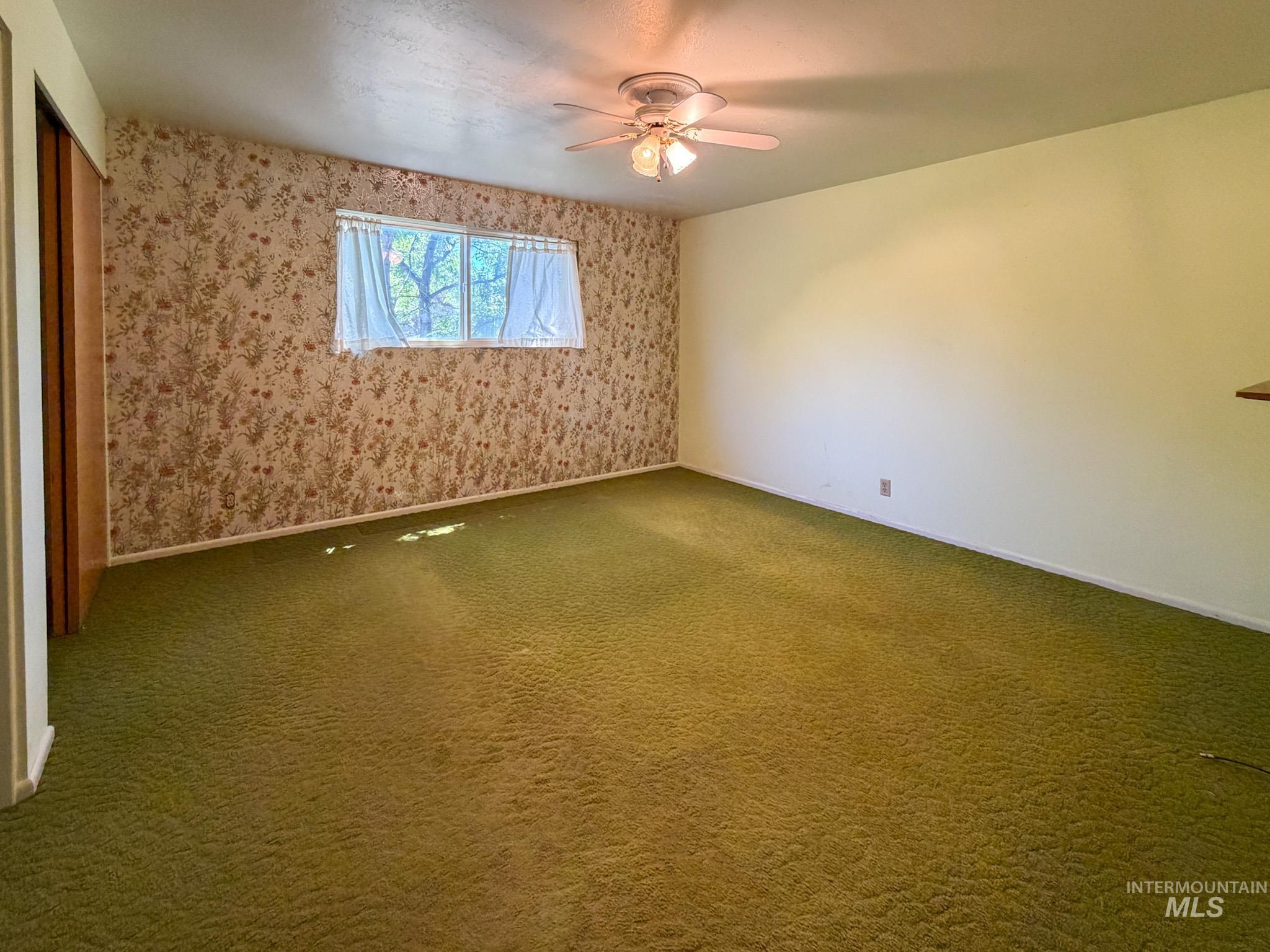 1924 H Street Rupert, ID 83350 - Photo 6 of 13 Bedroom featuring green carpeting, a patterned accent wall, a window with natural light, and a ceiling fan with integrated lighting