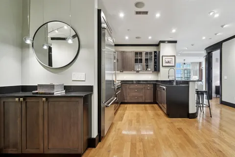 an open kitchen with kitchen island a sink and a stove with wooden floor