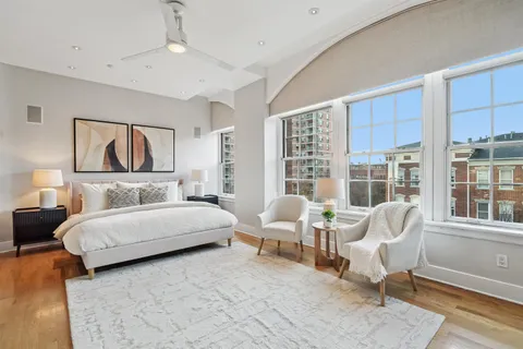 a bedroom with a bed and large windows