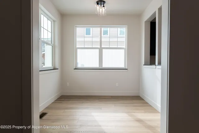 a view of a hallway with entryway and wooden floor