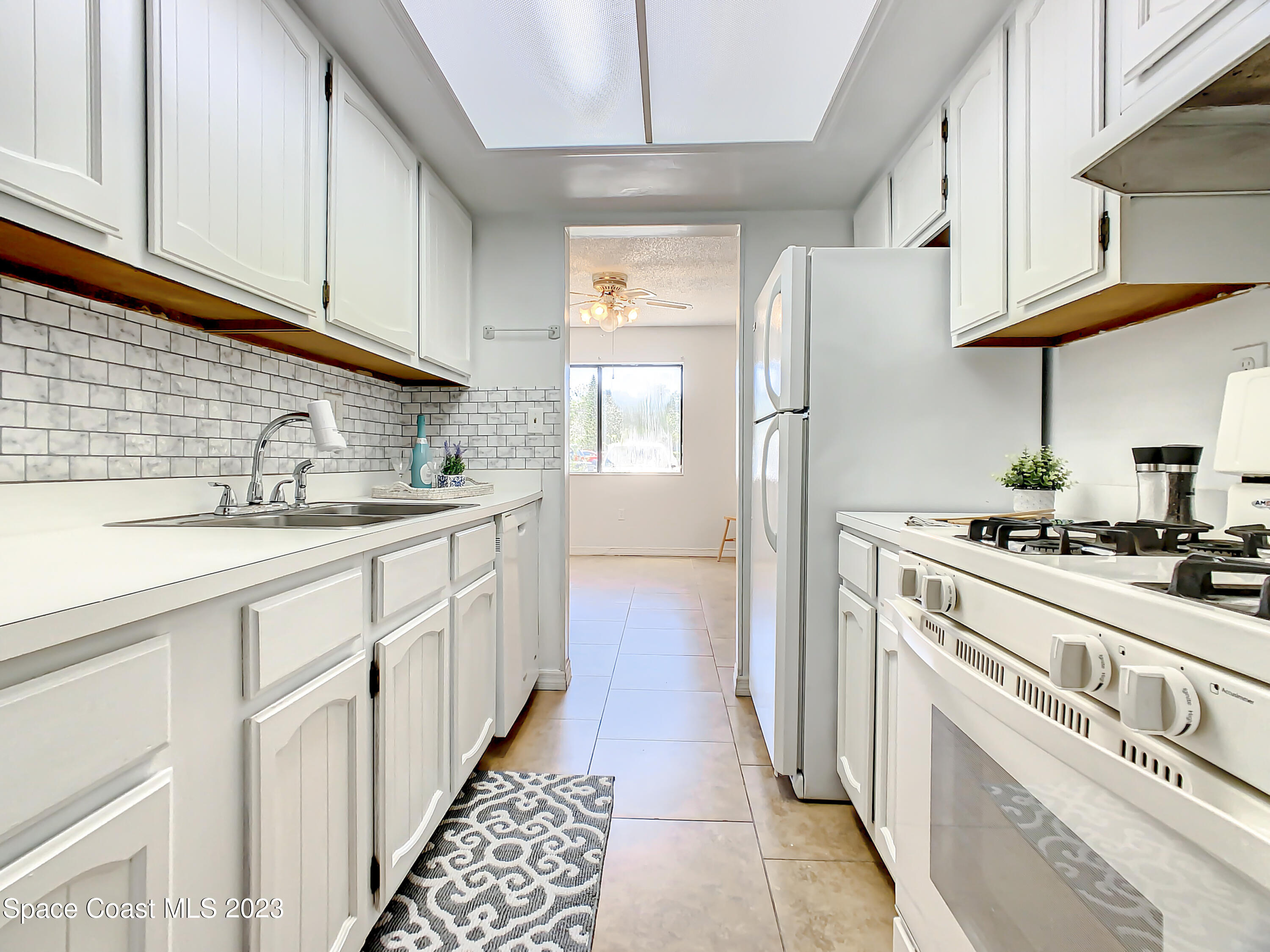 4859 Sisson Road Titusville, FL 32780 - Photo 9 of 30 a kitchen with white cabinets and white appliances