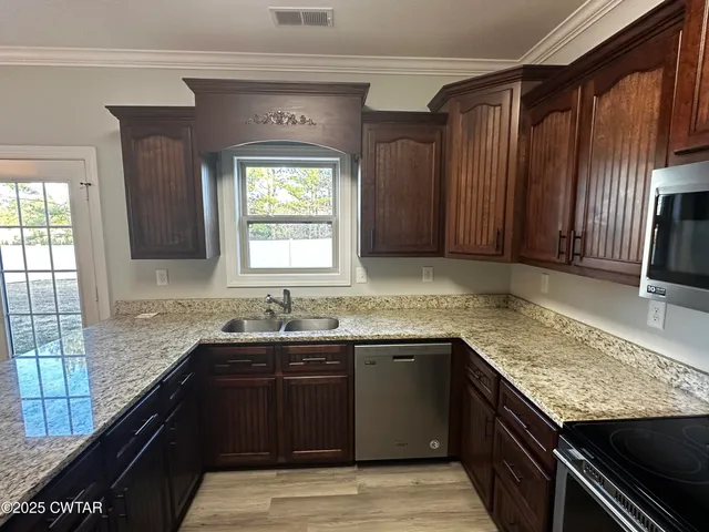 a kitchen with granite countertop a sink stove and cabinets