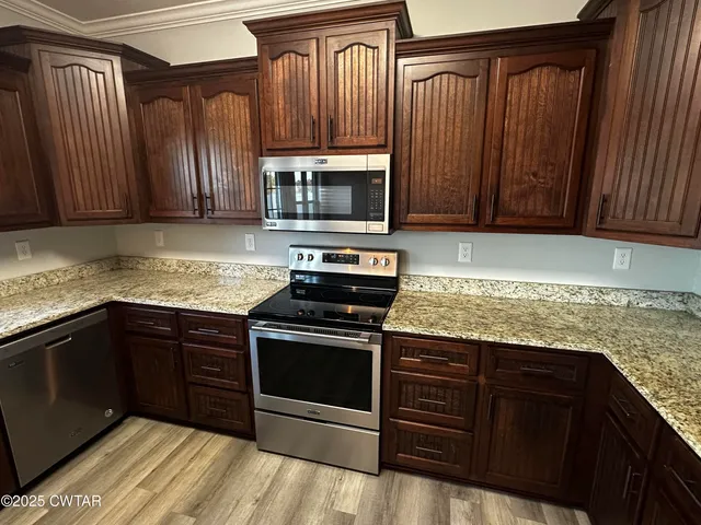 a kitchen with granite countertop wood cabinets and stainless steel appliances