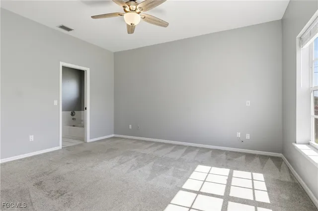 an empty room with windows and chandelier fan