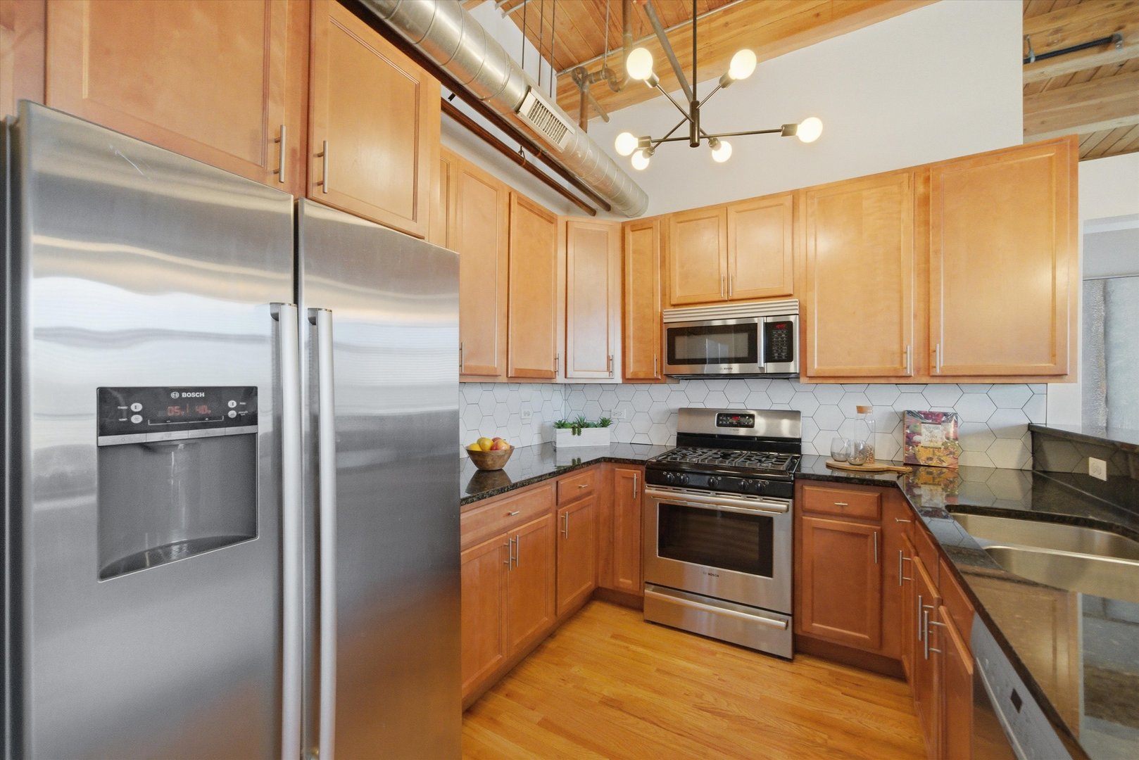 1610 South Halsted Street, Unit 401 Chicago, IL 60608 - Photo 8 of 31 a kitchen with stainless steel appliances granite countertop a stove a refrigerator a sink a microwave oven with cabinets and wooden floor