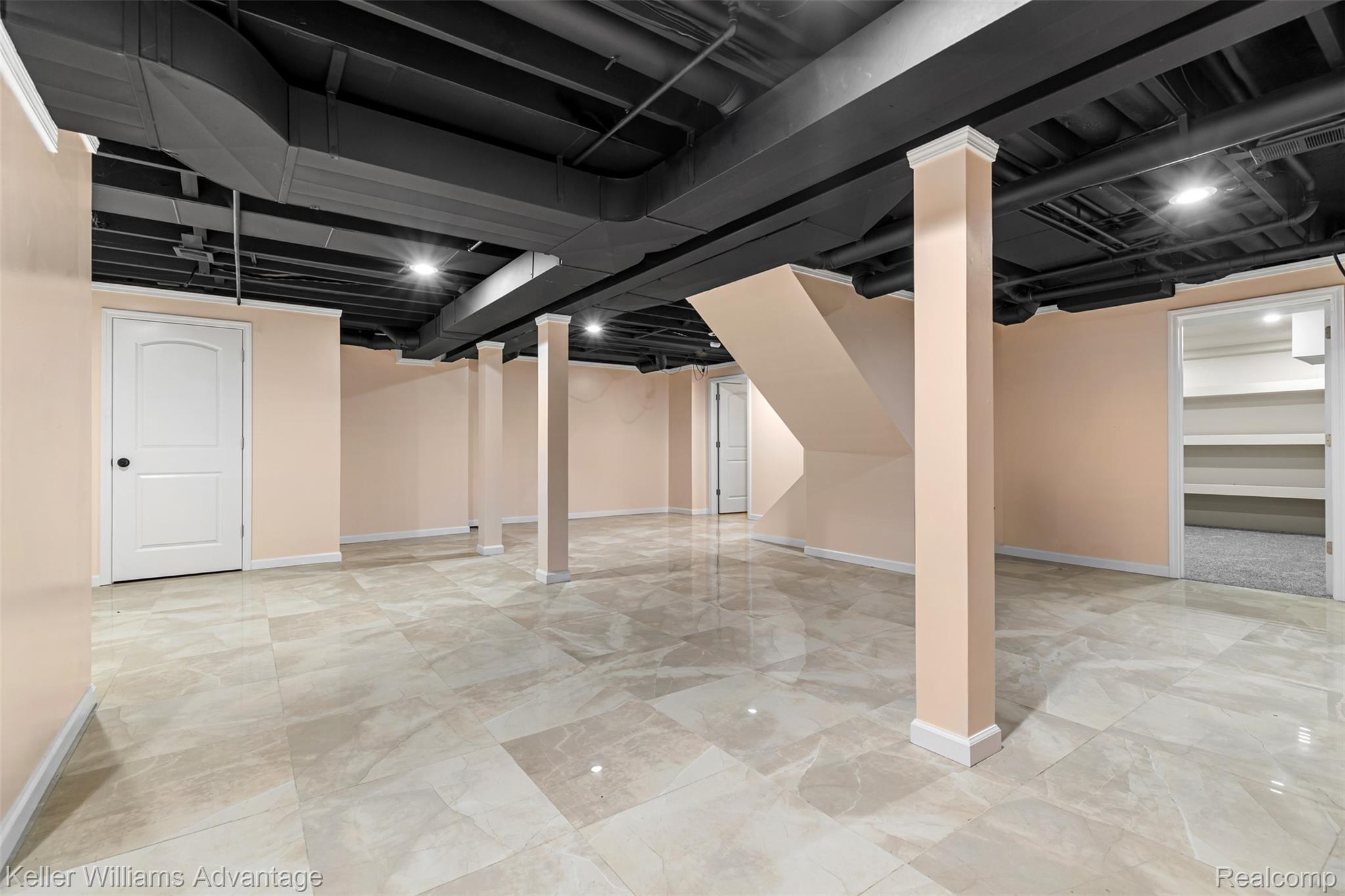 22627 Otter Road New Boston, MI 48164 - Photo 30 of 52 Spacious lower level featuring large format tile flooring, painted ceiling joists and ductwork, recessed lighting, support columns with decorative trim, and a finished staircase