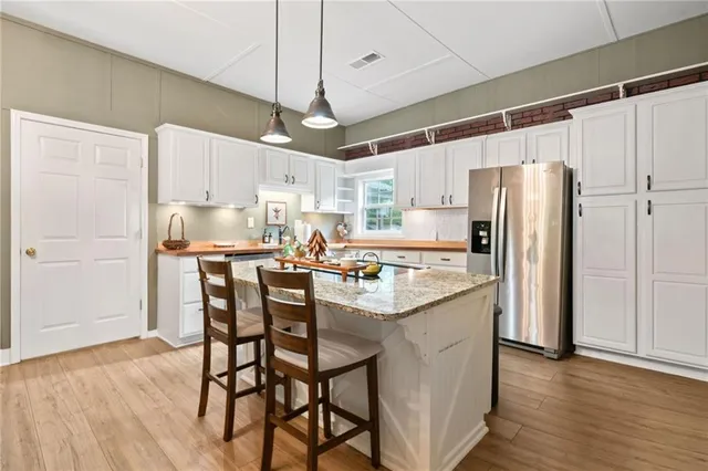 a kitchen with stainless steel appliances a dining table chairs refrigerator and microwave