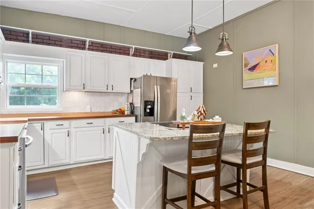 a kitchen with stainless steel appliances granite countertop a table chairs and a refrigerator