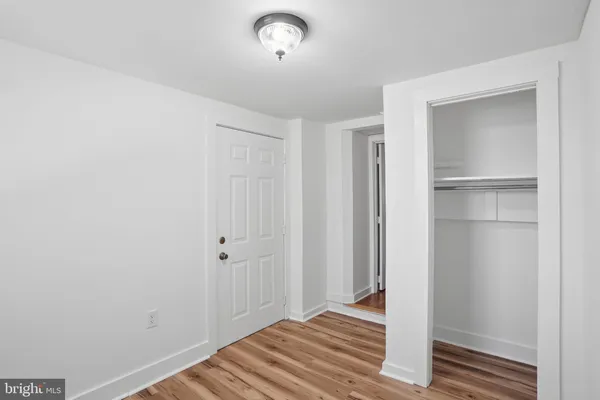 a view of a hallway with wooden floor and closet