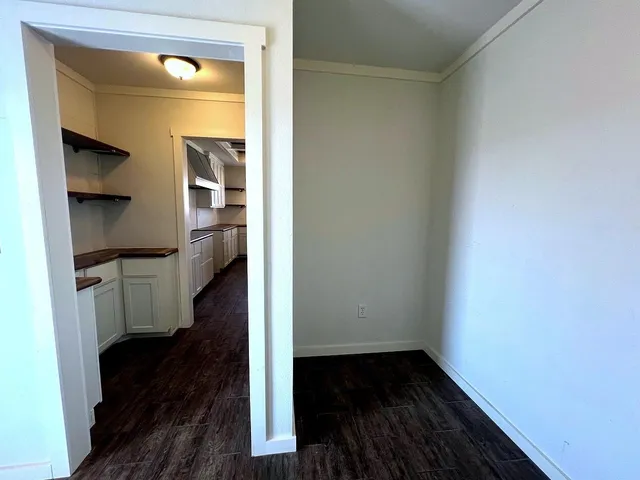 an empty room with wooden floor chandelier and windows