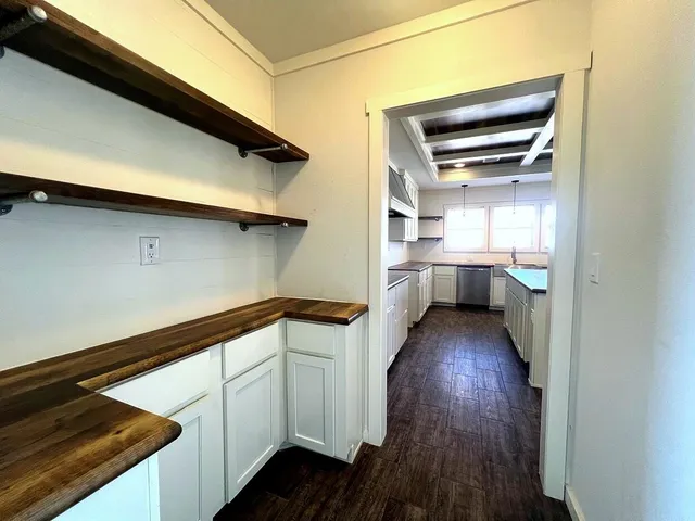 a kitchen with white cabinets and wooden floor