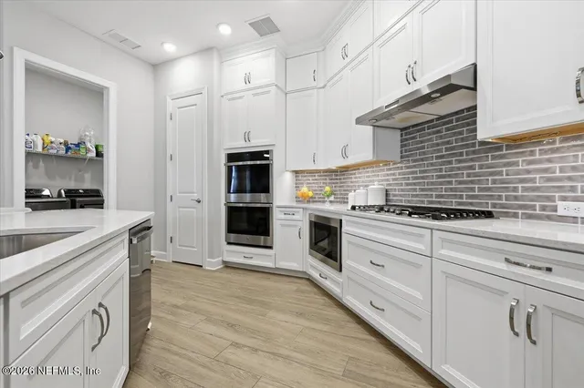 a kitchen with white cabinets and appliances