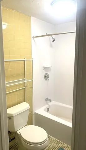 a white toilet sitting next to a bath tub and a shower