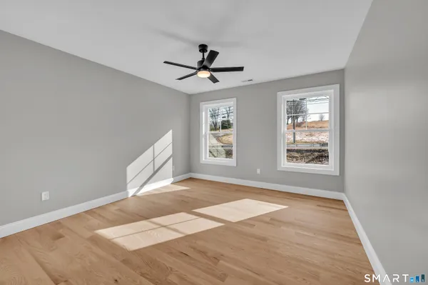 a view of empty room with wooden floor and fan