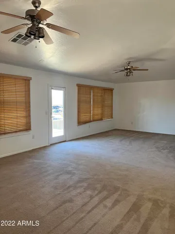 an empty room with a ceiling fan and windows