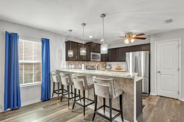 a kitchen with stainless steel appliances kitchen island granite countertop a table chairs and a refrigerator