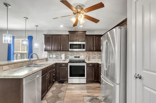 a kitchen with stainless steel appliances granite countertop a stove a sink and a refrigerator