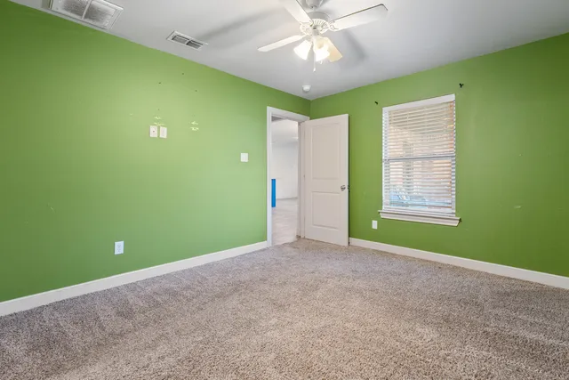 a view of an empty room with a window and a ceiling fan