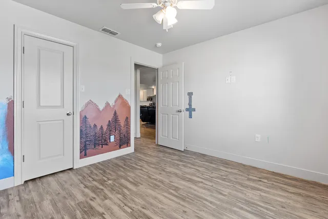 a view of a room with wooden floor and a ceiling fan